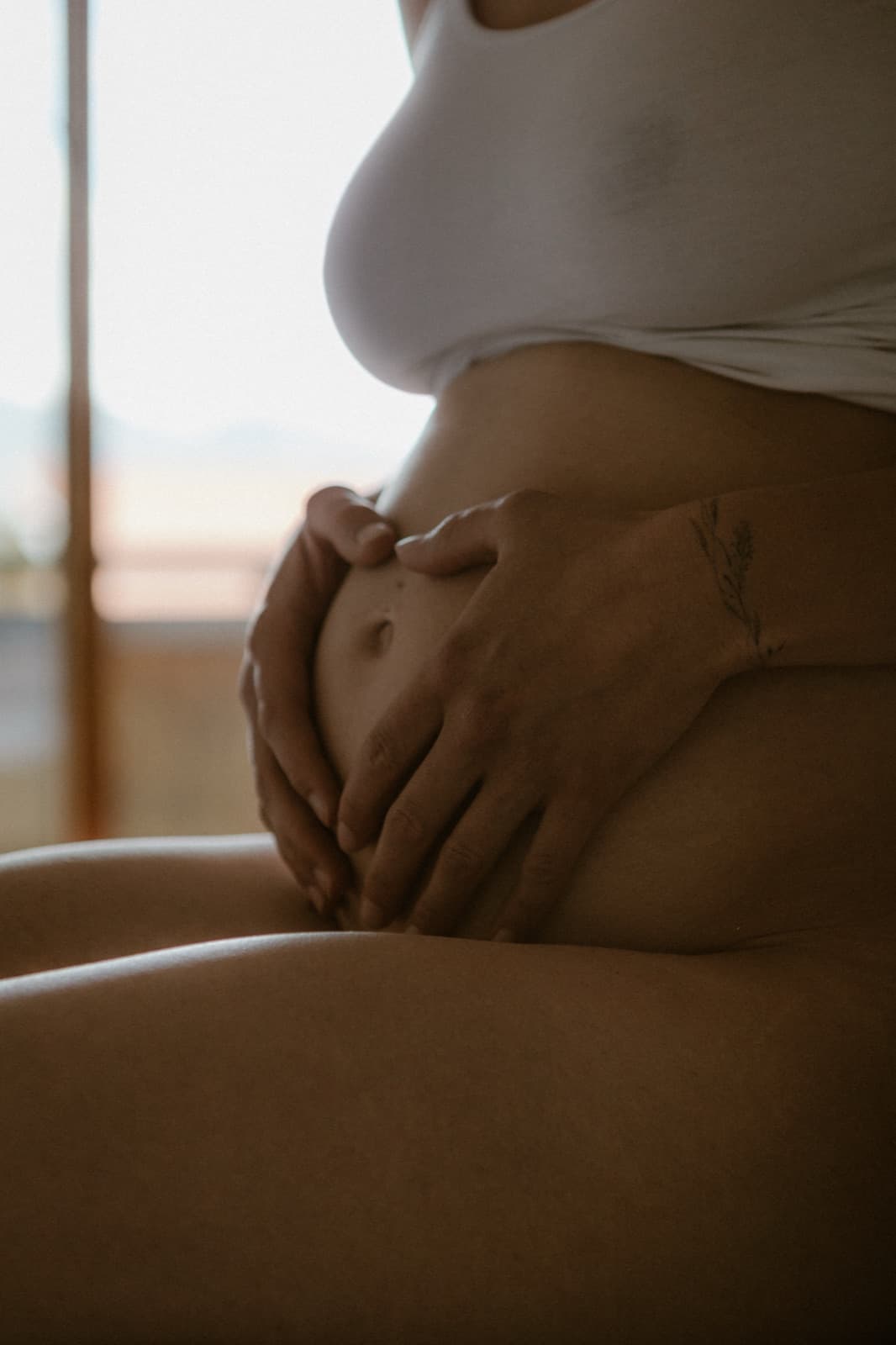 Hände formen ein Herz auf dem Bauch