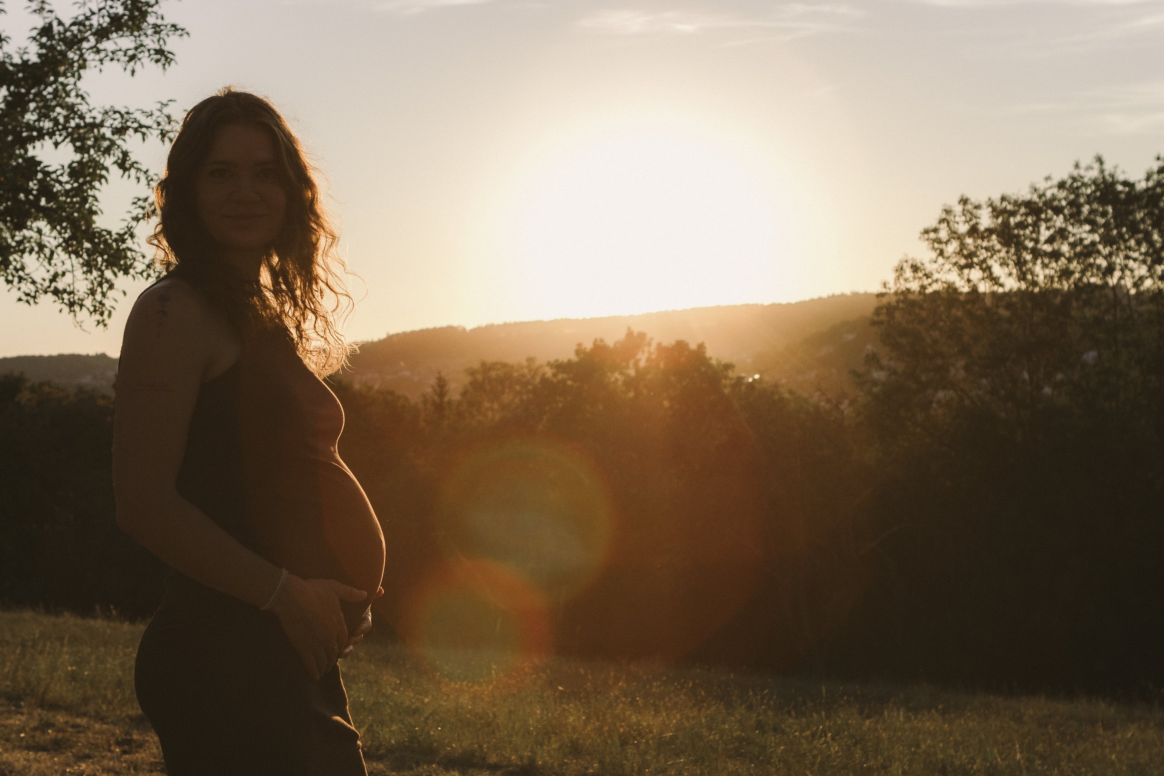 Werdende Mutter im Gegenlicht bei Sonnenuntergang